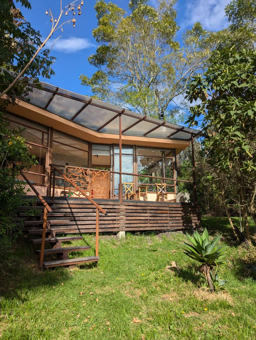 La cabaña con su terraza de madera, entre árboles